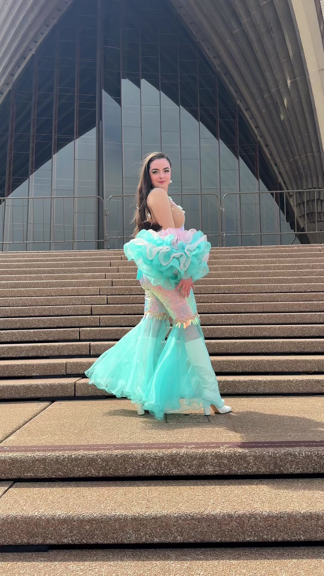 Abbey in a mint-green ruffled ABBA-style costume posing on the steps of the Sydney Opera House