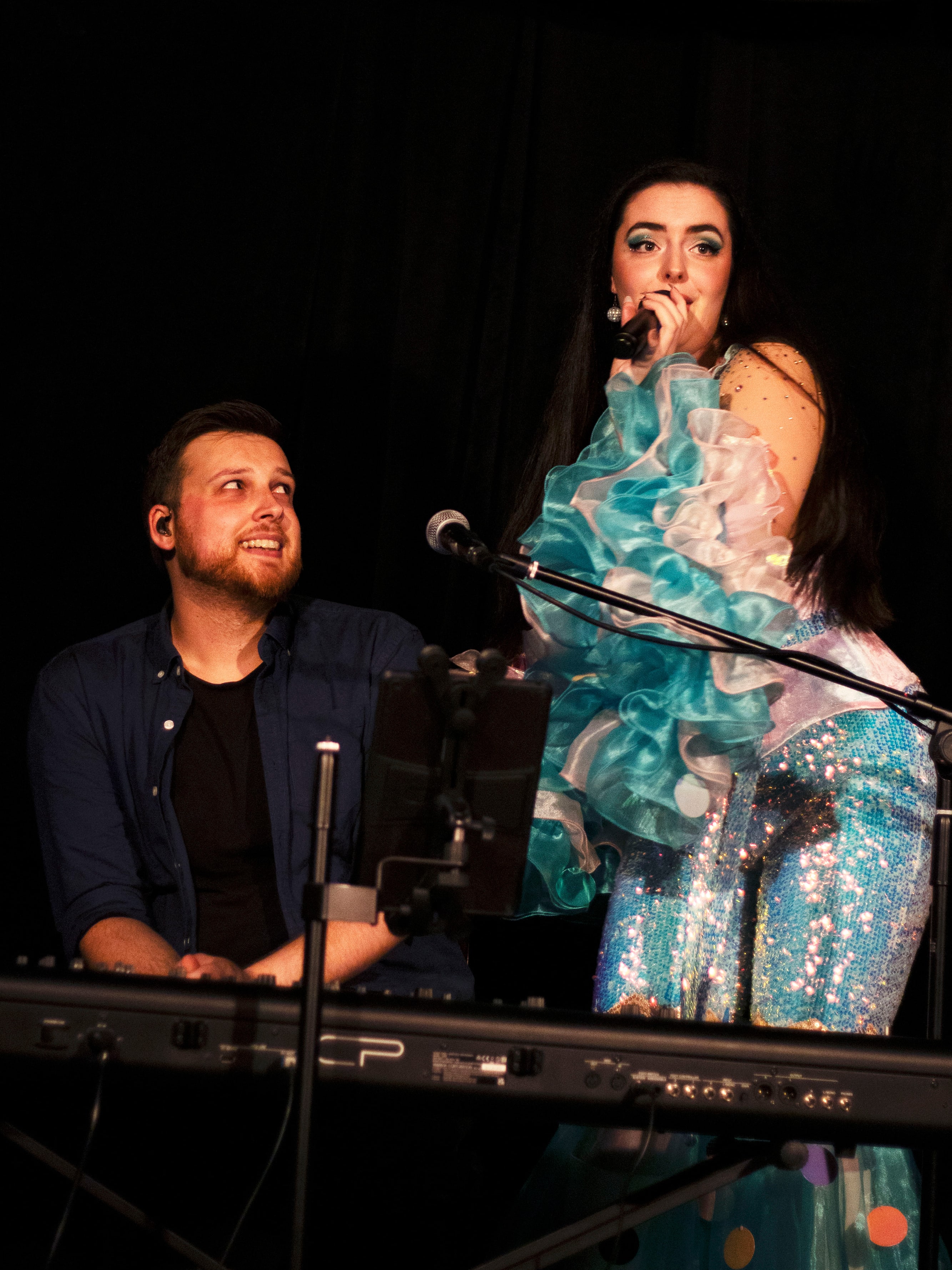 Abbey singing beside her pianist at the keyboard