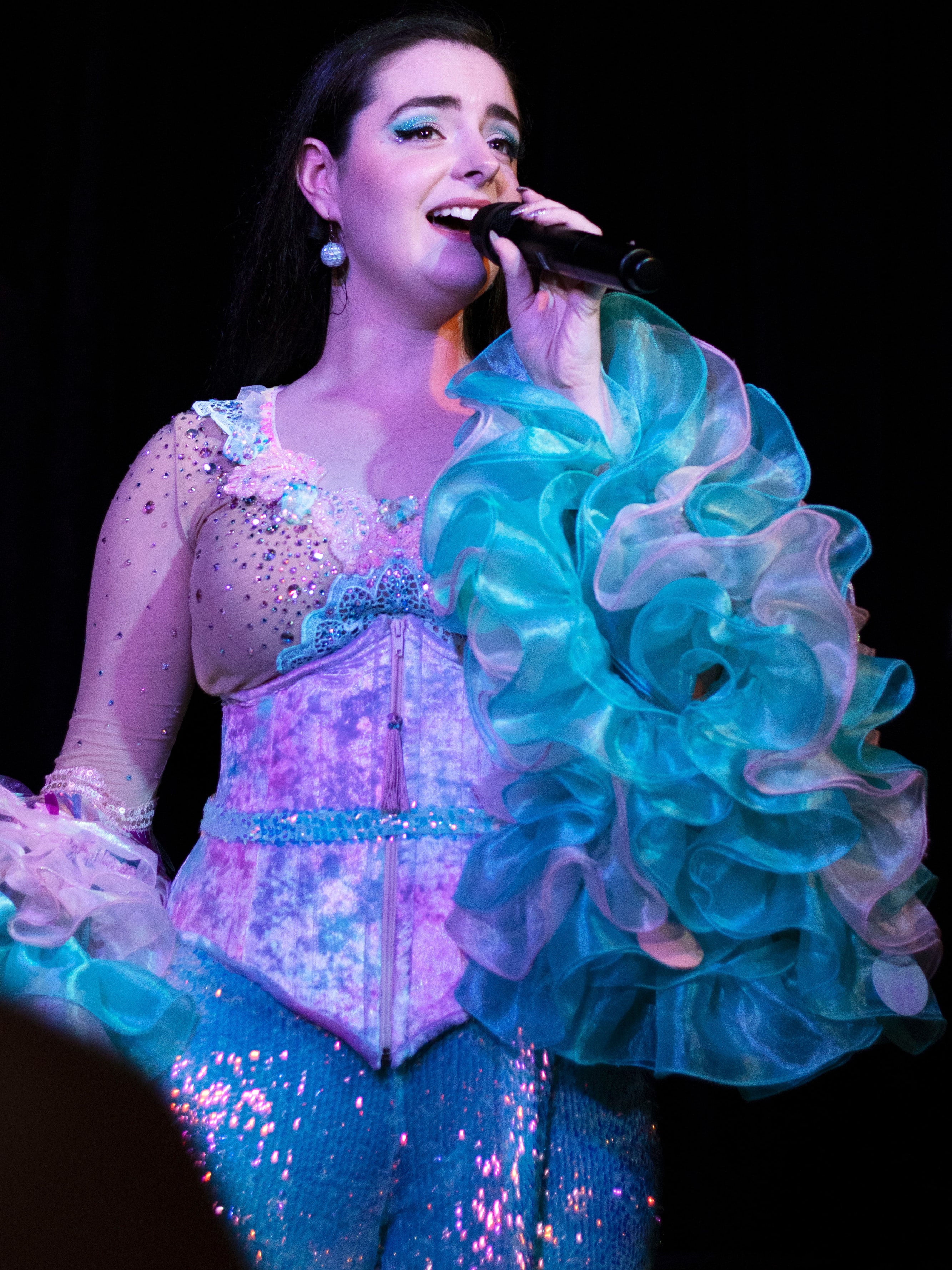 Abbey singing in her corset and aqua ruffled sleeves