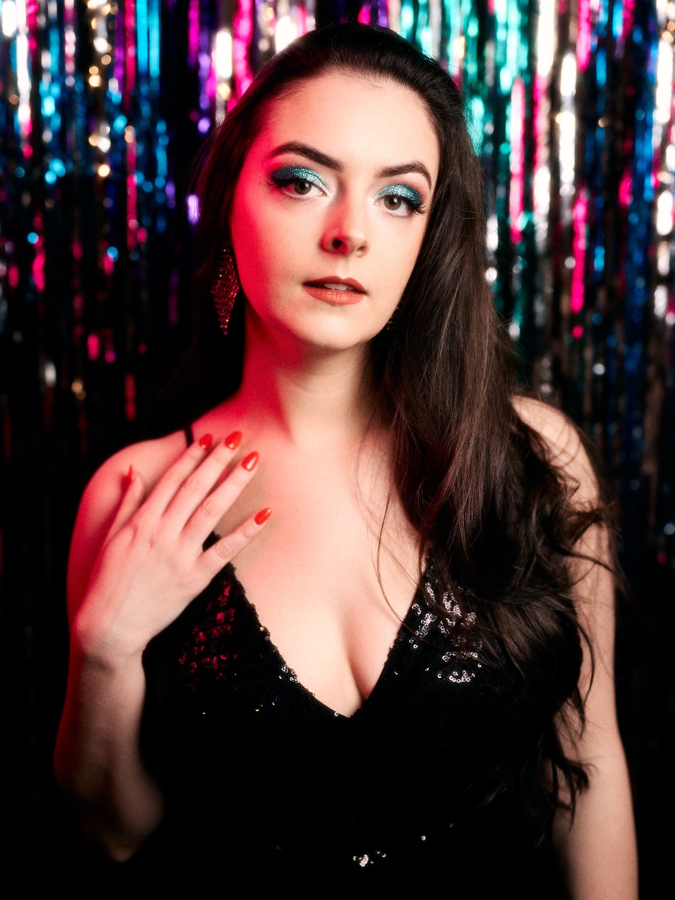 Abbey in a black sequin dress in front of a multicoloured tinsel curtain
