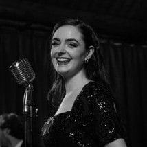 Abbey smiling beside a vintage microphone