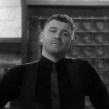 Casey in a black shirt and tie