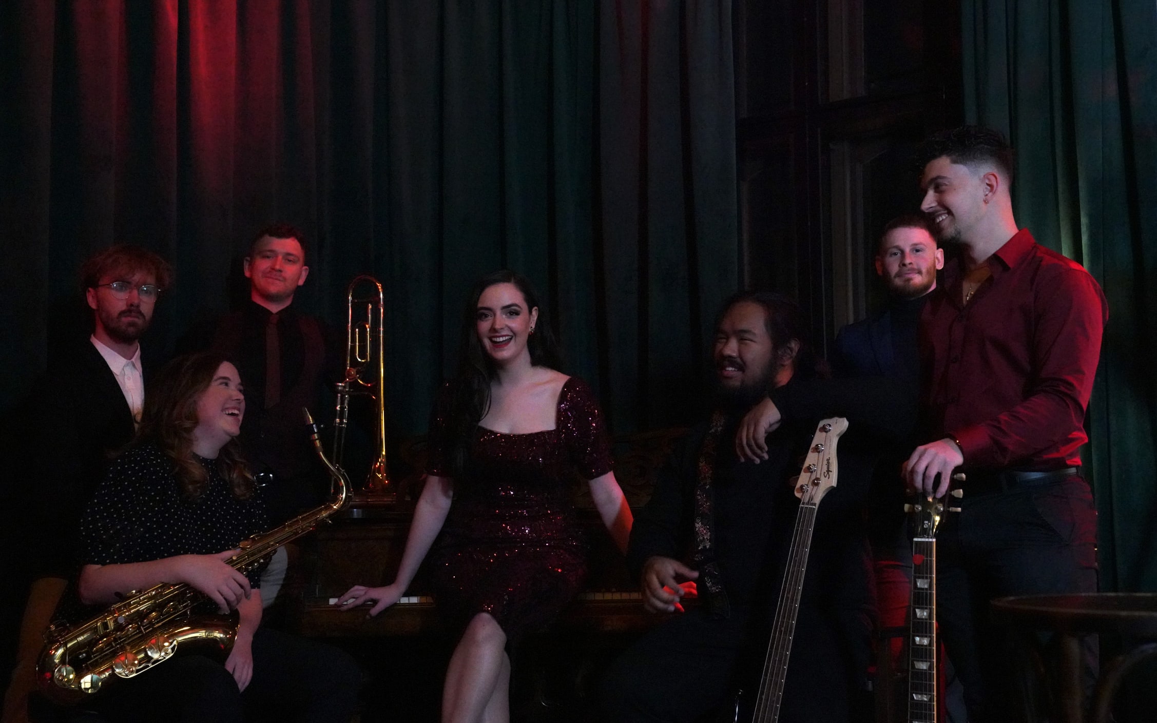 Cherry Lane gathered together holding their instruments, Abbey seated in the centre in a sequin dress
