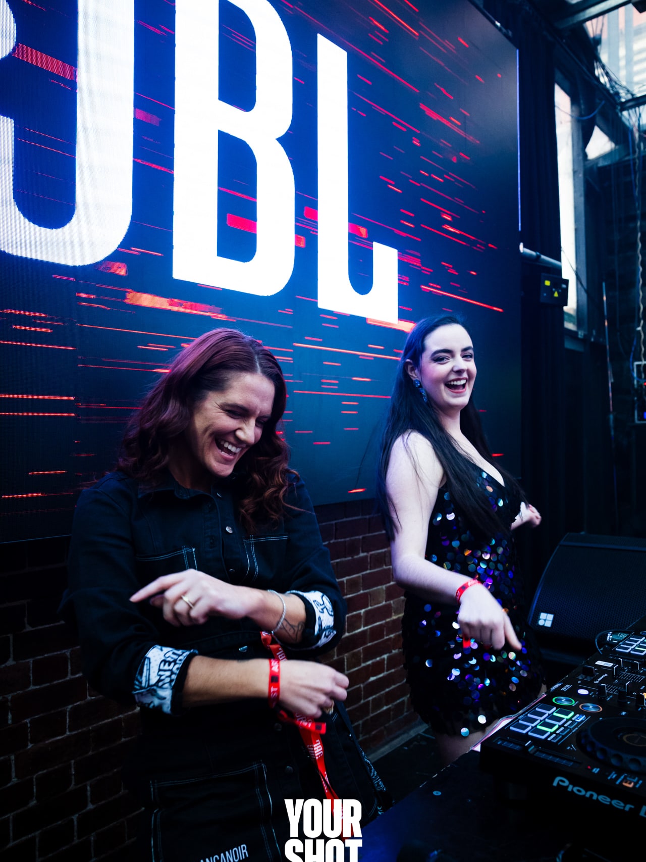 Abbey and Cass dancing behind the decks in the JBL DJ booth