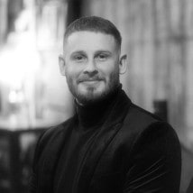 Jordan smiling in a black turtleneck and jacket
