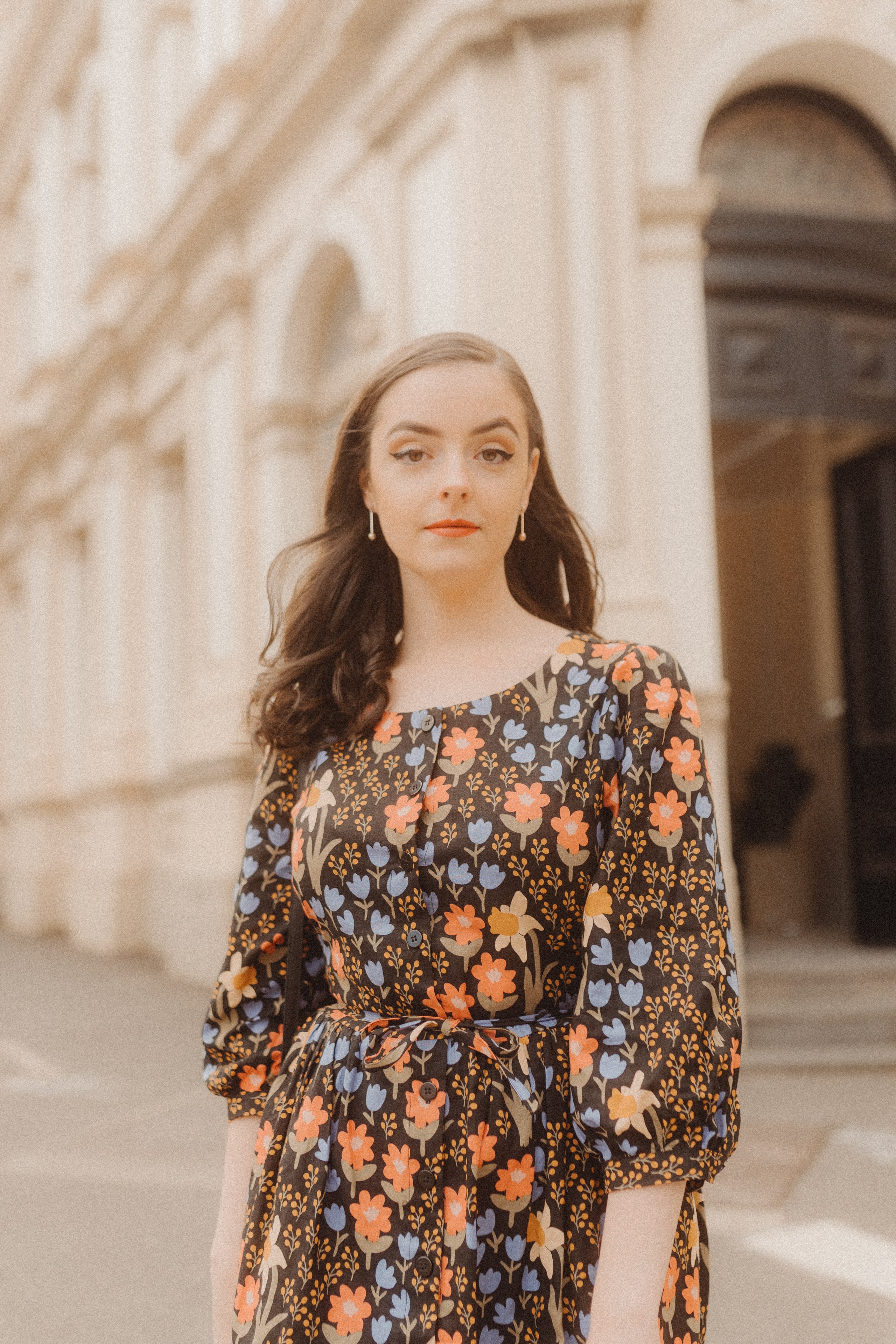 Abbey in a floral midi dress standing in front of an old sandstone building