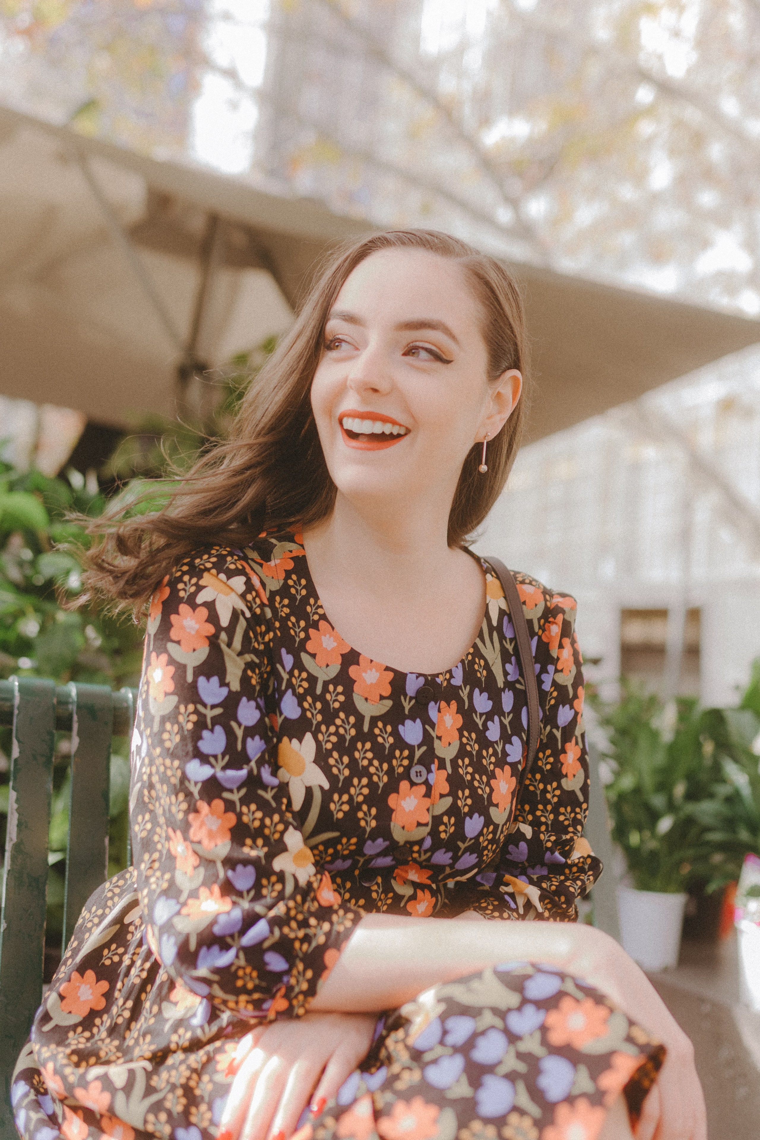 Abbey laughing in a floral dress at an outdoor cafe