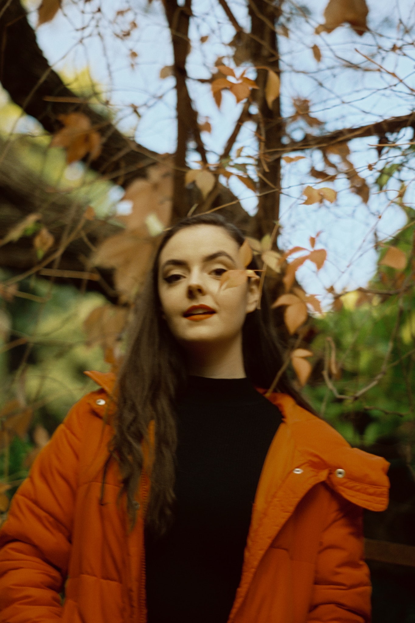 Abbey in an orange puffer jacket among autumn leaves