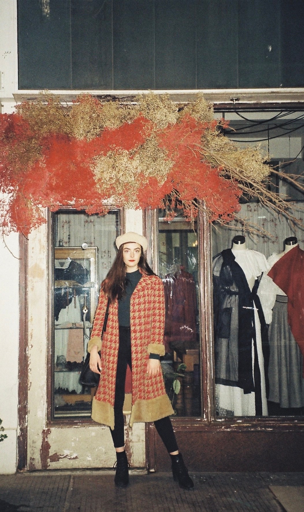 Abbey in a red houndstooth coat and beret outside a vintage clothing shopfront