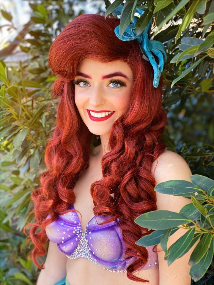 Abbey in costume as a red-haired mermaid princess with a purple shell top, surrounded by leaves