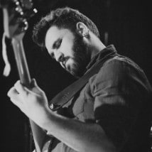 Nicholas playing bass guitar, head bowed