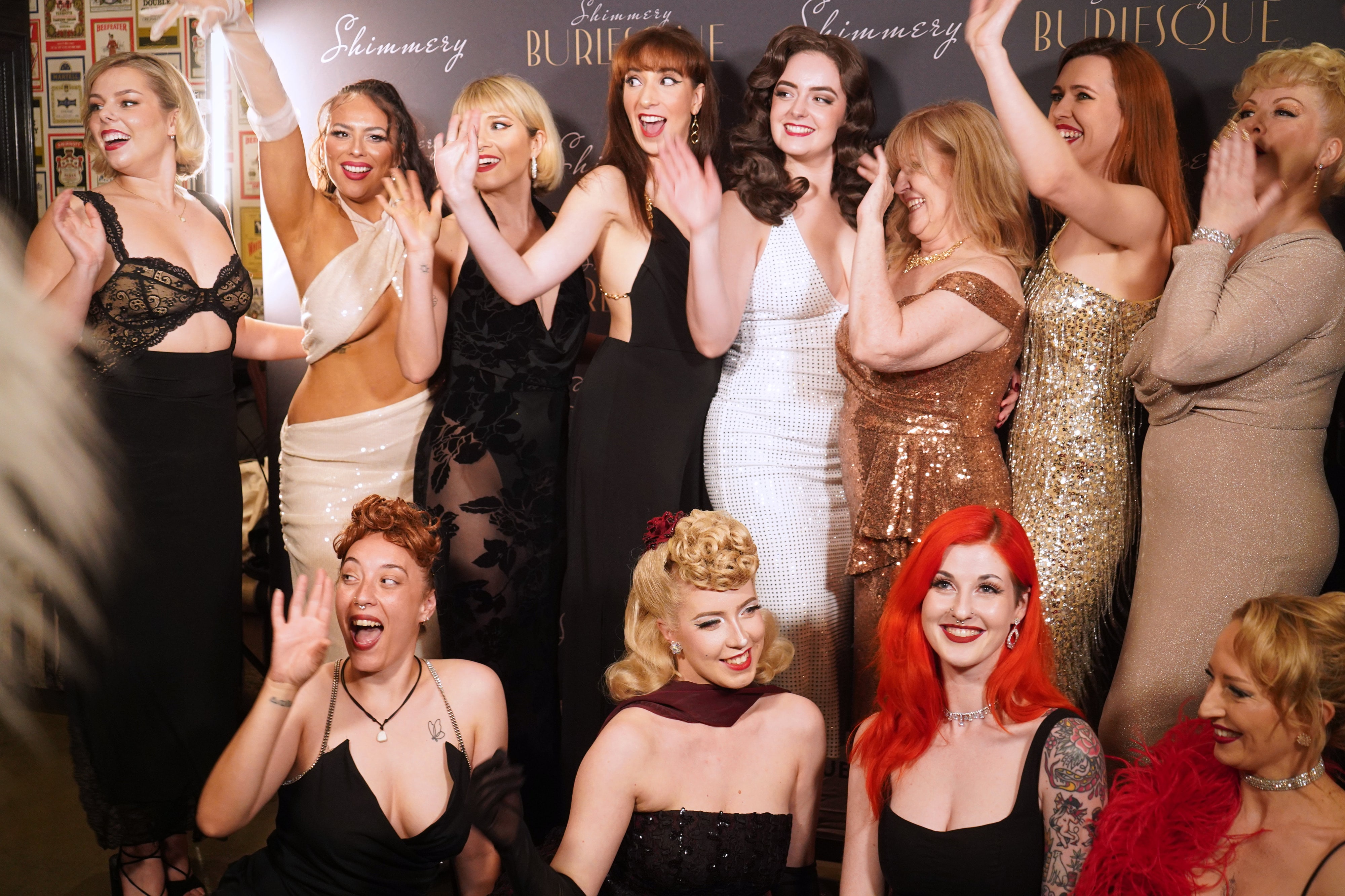 Abbey and cast members laughing together in front of the Shimmery Burlesque media wall