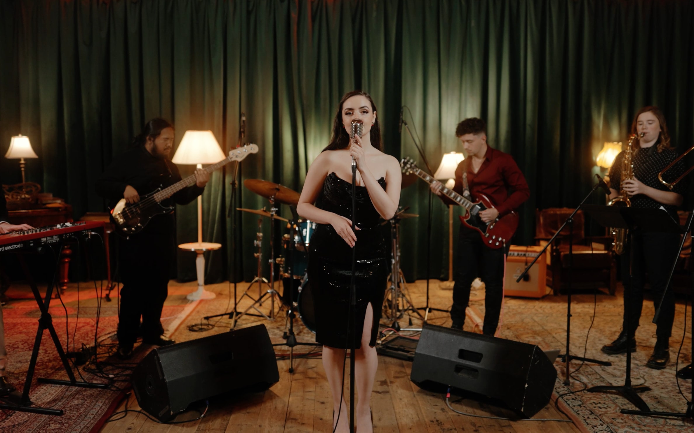 Abbey singing in a black dress at the front of the seven-piece Cherry Lane band, lamps glowing on stage