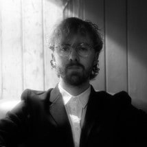 Thomas in round glasses and a dark jacket